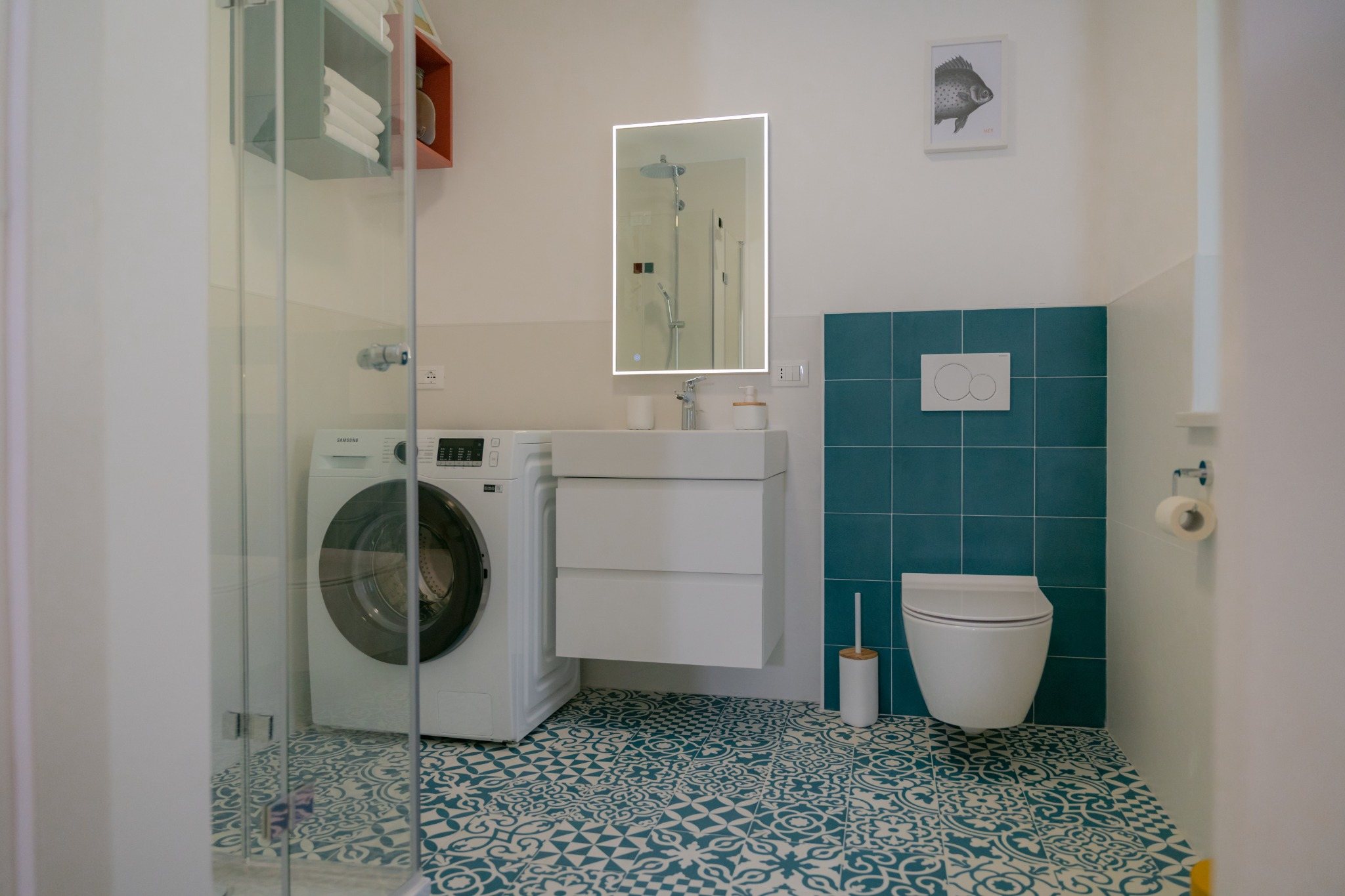 Modernes Bad mit Dusche, Waschbecken, Waschmaschine, WC und türkisfarbenen Fliesen.