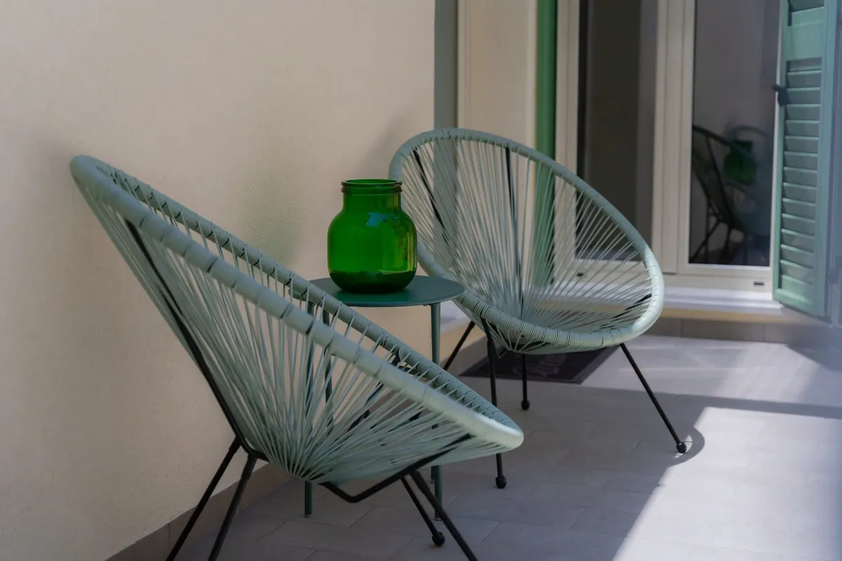 Zwei helle Außenstühle mit kleinem Tisch vor der Ferienwohnung.